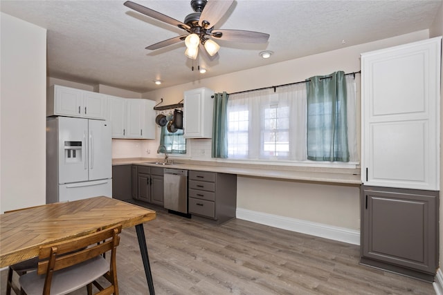 kitchen with gray cabinetry, white refrigerator with ice dispenser, white cabinetry, light countertops, and stainless steel dishwasher