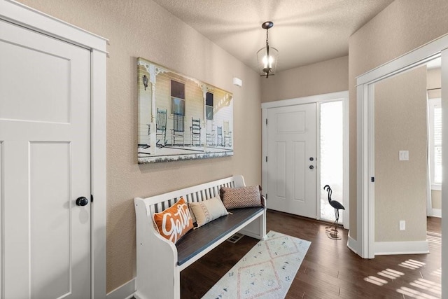 entryway featuring a textured ceiling, baseboards, dark wood-type flooring, and a textured wall