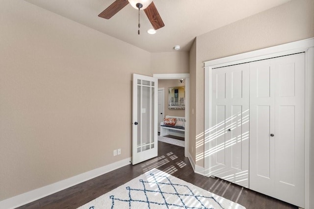 bedroom with dark wood-type flooring, a closet, ceiling fan, and baseboards