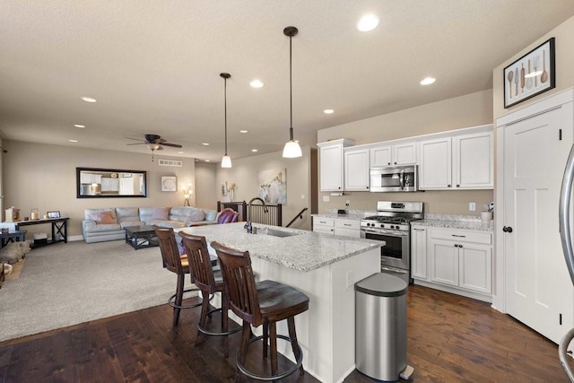 kitchen with white cabinetry, appliances with stainless steel finishes, open floor plan, and pendant lighting