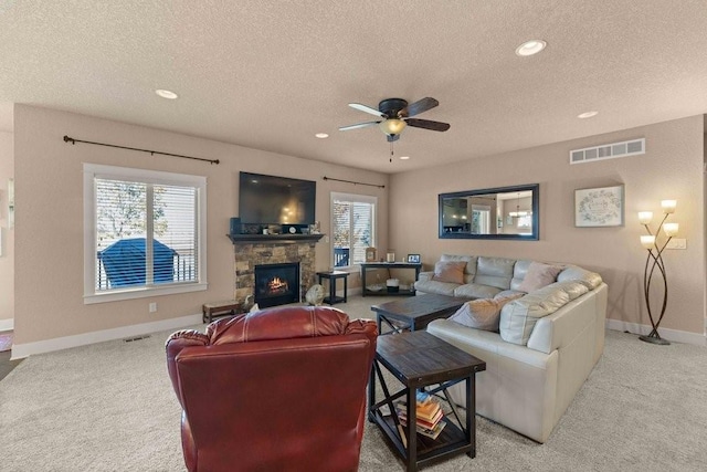 living room with a wealth of natural light, a fireplace, visible vents, and light colored carpet