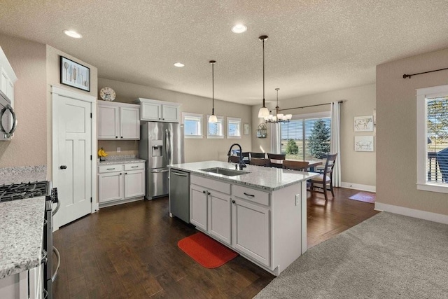 kitchen featuring appliances with stainless steel finishes, an island with sink, a sink, and white cabinets