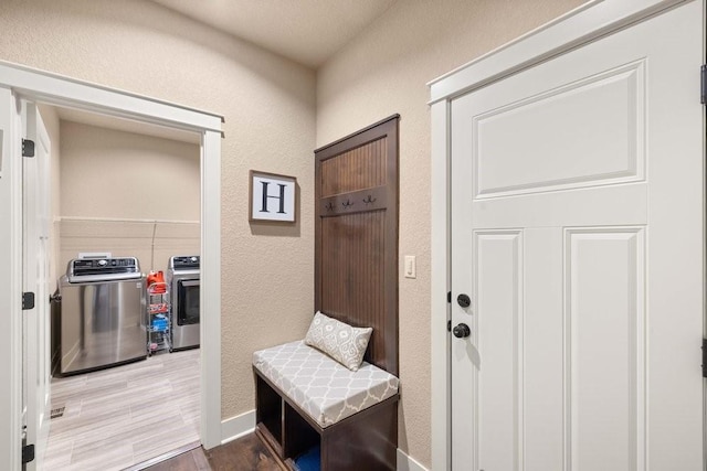 mudroom featuring a textured wall, wood finished floors, and independent washer and dryer