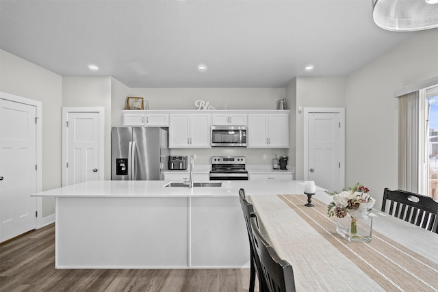 kitchen featuring a center island with sink, stainless steel appliances, light countertops, white cabinetry, and a sink