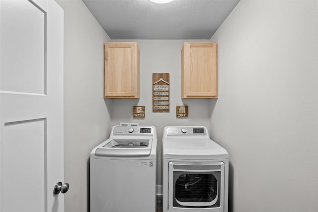 laundry area with cabinet space, washer and clothes dryer, and a textured ceiling