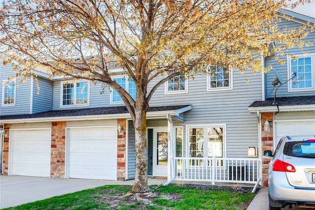 multi unit property featuring driveway, stone siding, an attached garage, and a porch