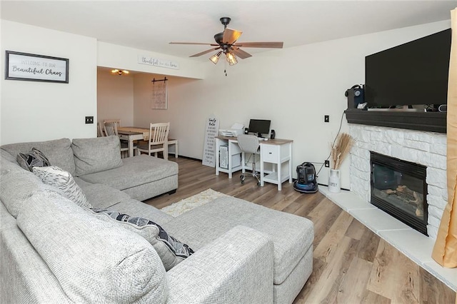 living area featuring ceiling fan, a fireplace, and wood finished floors