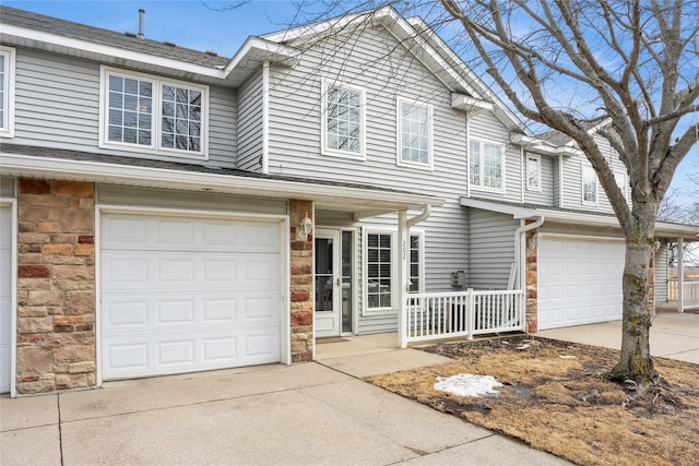 view of property featuring stone siding, driveway, and an attached garage