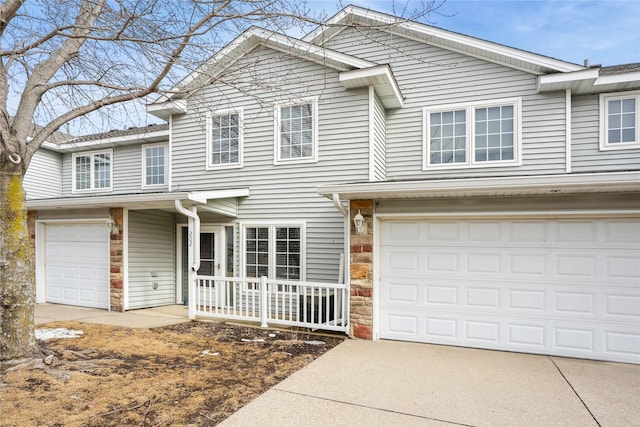 traditional home with a garage, stone siding, covered porch, and driveway