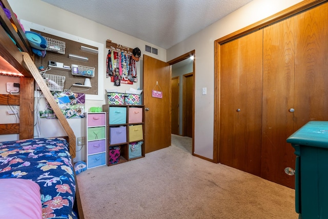 bedroom featuring carpet floors, a closet, visible vents, and a textured ceiling