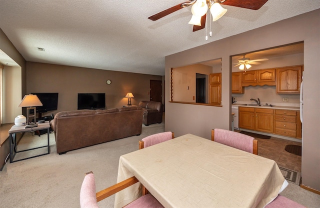 dining room with a ceiling fan, visible vents, light colored carpet, and a textured ceiling