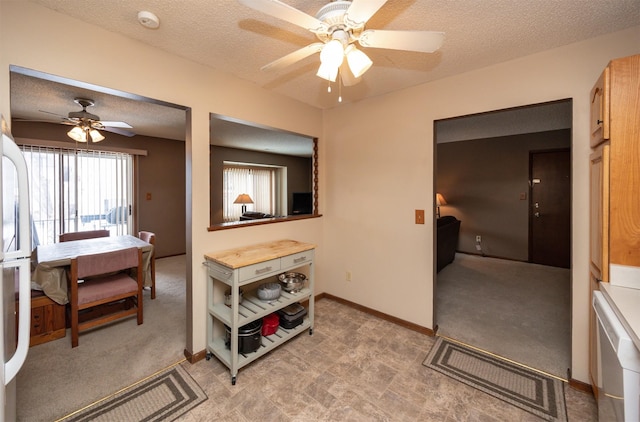 interior space with a textured ceiling, light carpet, a ceiling fan, and baseboards