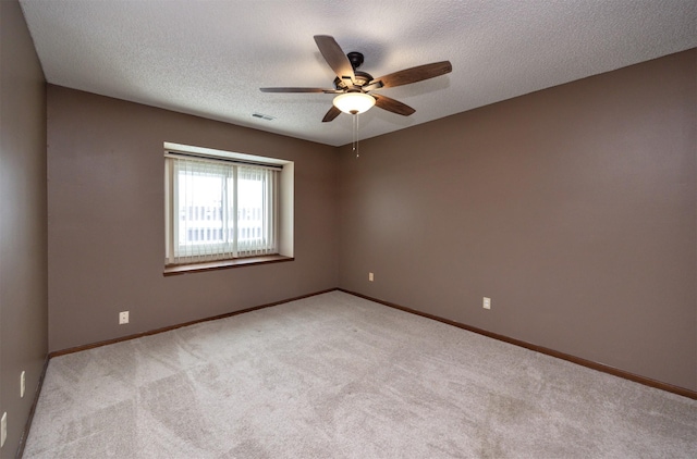 unfurnished room with ceiling fan, a textured ceiling, light colored carpet, visible vents, and baseboards