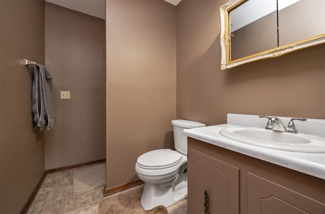 half bath with toilet, baseboards, and vanity