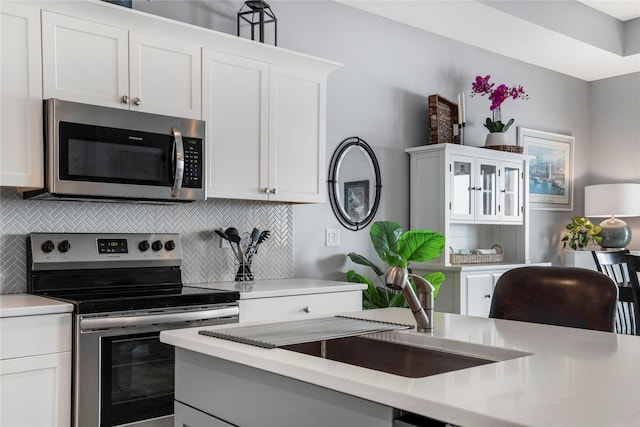 kitchen with stainless steel appliances, light countertops, and white cabinets