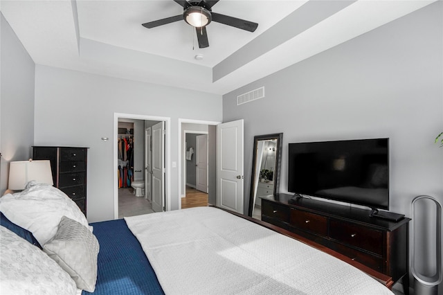 bedroom with visible vents, a raised ceiling, a ceiling fan, a spacious closet, and a closet