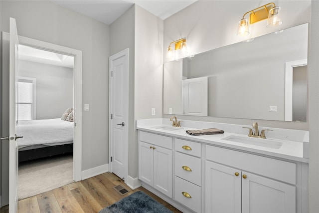 bathroom featuring wood finished floors, visible vents, a sink, and ensuite bathroom