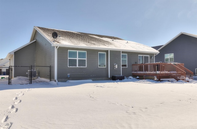 snow covered rear of property with a deck and fence