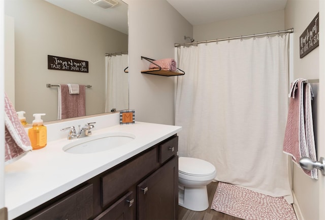 full bathroom with toilet, visible vents, wood finished floors, and vanity