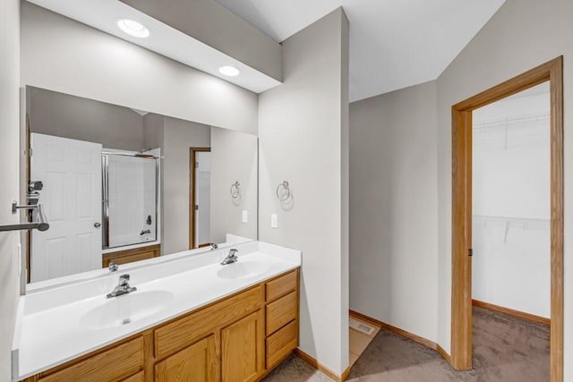 full bath featuring a sink, double vanity, a walk in closet, and baseboards