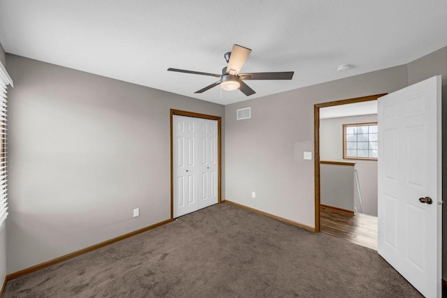 unfurnished bedroom featuring dark colored carpet, a closet, visible vents, and baseboards