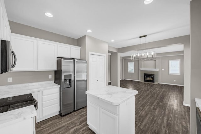 kitchen with stainless steel appliances, a center island, white cabinetry, and light stone counters