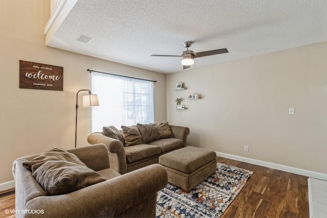 living room with dark wood-style flooring, ceiling fan, a textured ceiling, and baseboards