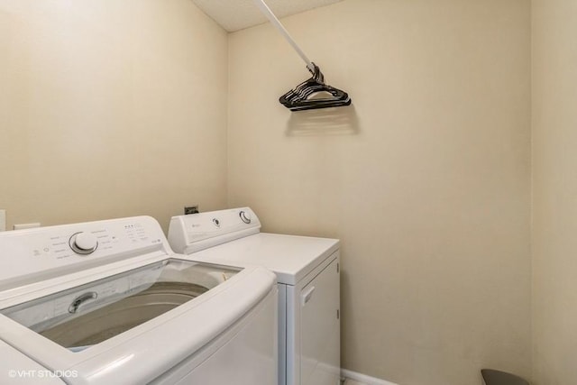 clothes washing area featuring laundry area, baseboards, and washer and clothes dryer