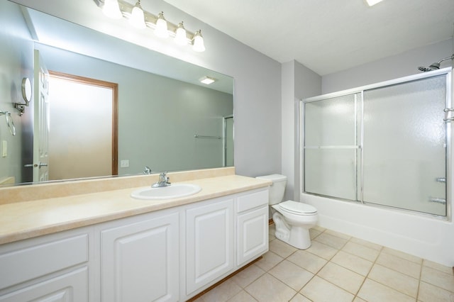 full bath with toilet, bath / shower combo with glass door, tile patterned flooring, and vanity