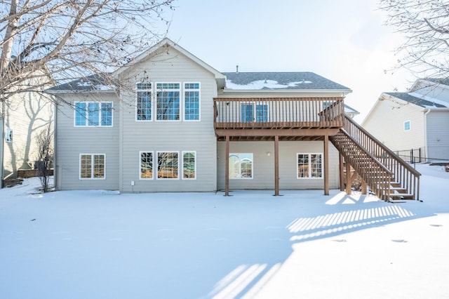 snow covered back of property featuring stairs and a wooden deck