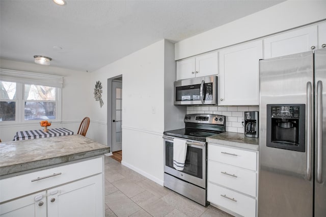 kitchen featuring tasteful backsplash, appliances with stainless steel finishes, light countertops, a textured ceiling, and white cabinetry