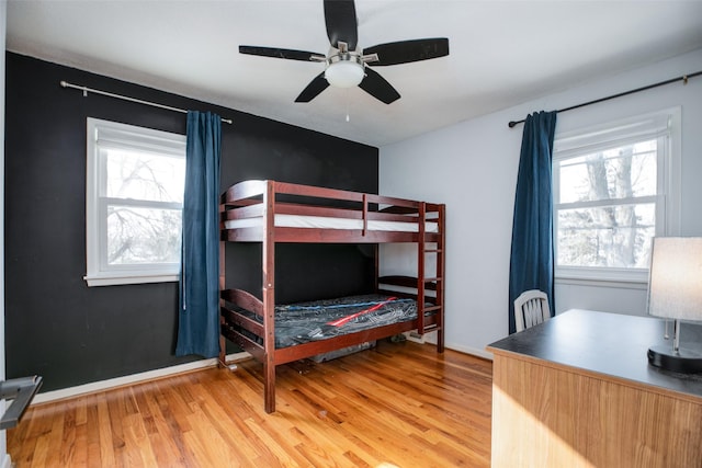 bedroom featuring light wood finished floors, baseboards, and a ceiling fan