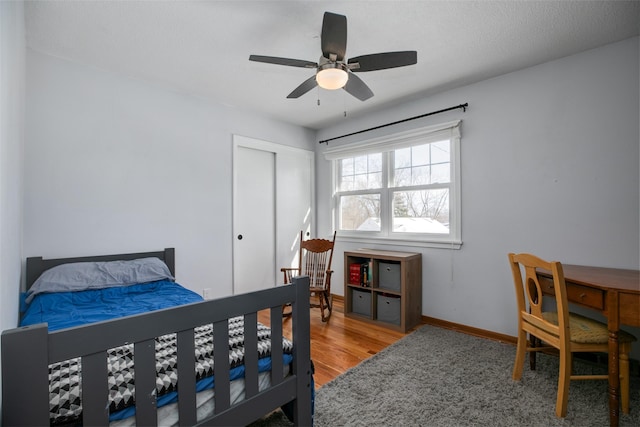 bedroom featuring a closet, ceiling fan, baseboards, and wood finished floors