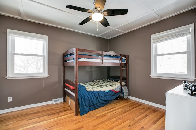 bedroom featuring light wood-style floors, visible vents, baseboards, and a ceiling fan