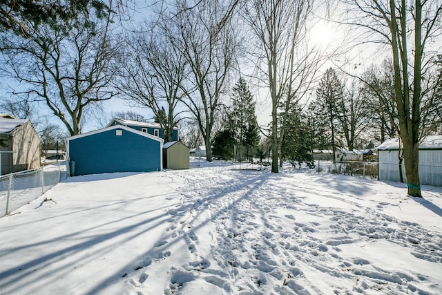 yard layered in snow featuring an outdoor structure, fence, and a shed