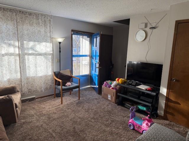 living area featuring a textured ceiling, carpet floors, and visible vents