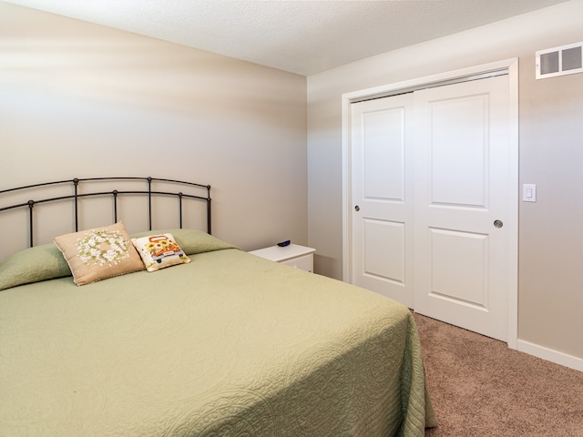 bedroom featuring a closet, visible vents, baseboards, and light carpet
