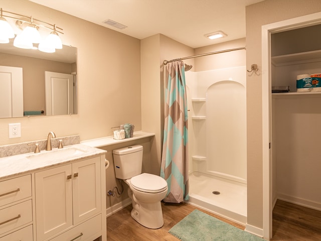 full bathroom with wood finished floors, a stall shower, vanity, toilet, and visible vents