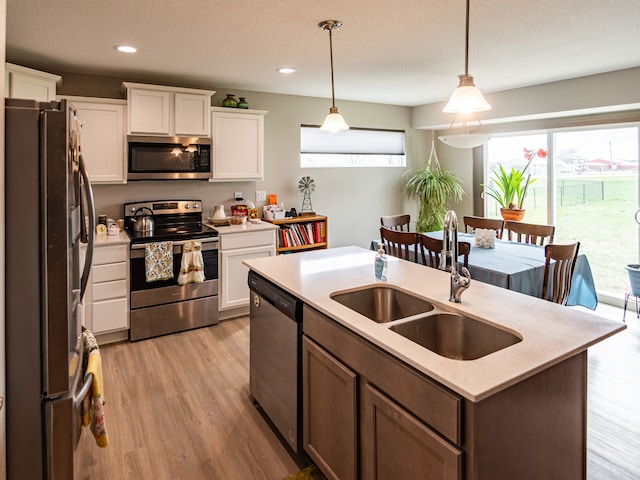 kitchen featuring a sink, white cabinetry, light countertops, an island with sink, and appliances with stainless steel finishes