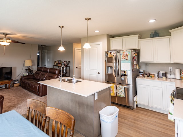 kitchen with a sink, open floor plan, ceiling fan, stainless steel fridge with ice dispenser, and light countertops