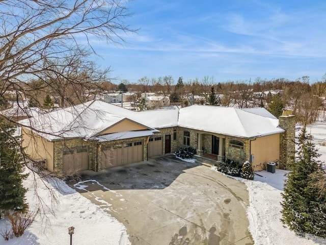 ranch-style house featuring stone siding, concrete driveway, central AC, and an attached garage