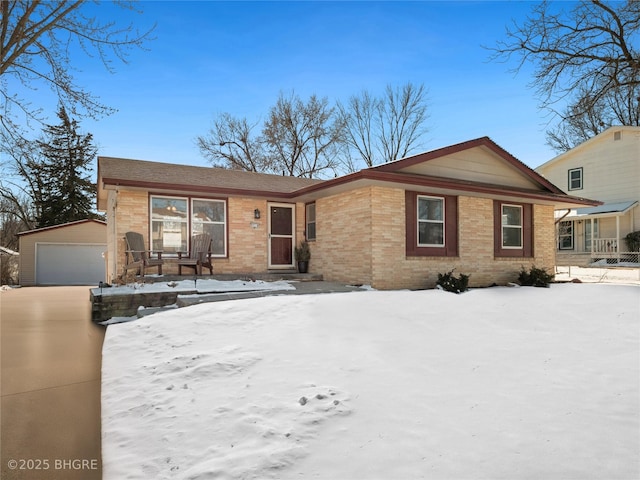 view of front of property featuring a garage, brick siding, and an outbuilding