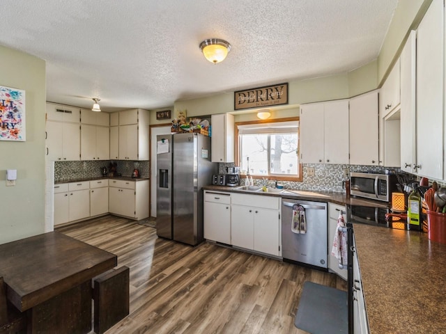 3473 Juniper Ave, Casey, IA 50048 - kitchen with stainless steel appliances, a textured ceiling, dark countertops, visible vents, and decorative backsplash
