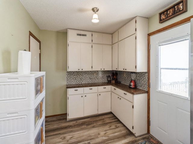 3473 Juniper Ave, Casey, IA 50048 - kitchen with dark countertops, wood finished floors, visible vents, decorative backsplash, and white cabinetry