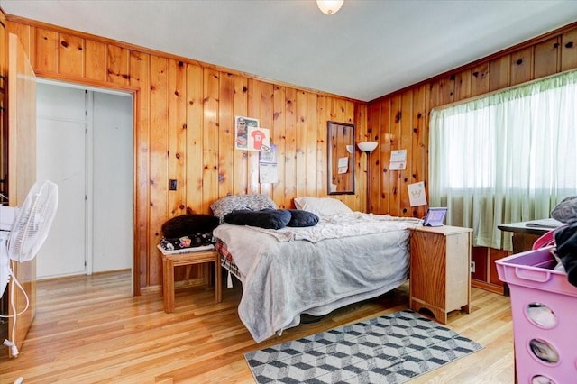 bedroom with light wood-style floors and wooden walls