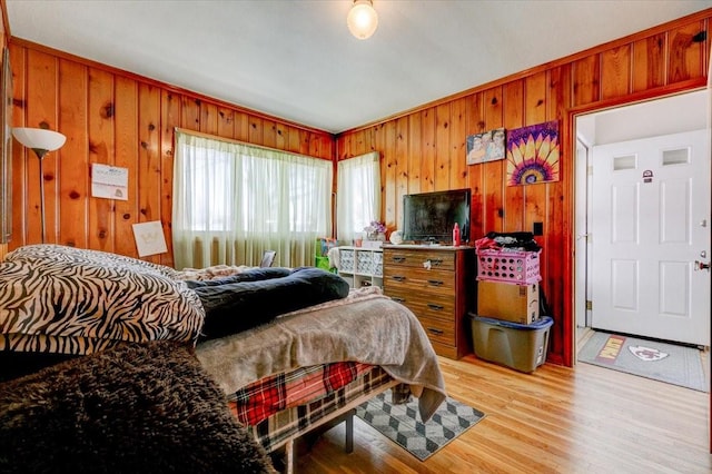 bedroom featuring light wood-type flooring and wooden walls