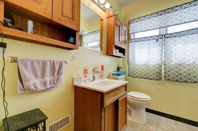 bathroom with toilet, vanity, visible vents, and baseboards