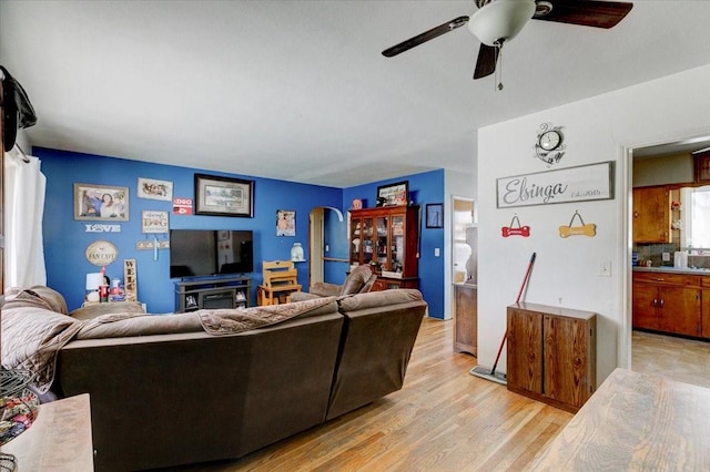 living room with arched walkways, ceiling fan, and light wood finished floors