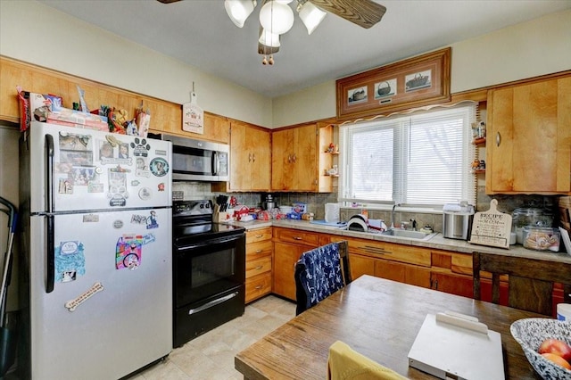 kitchen featuring stainless steel microwave, brown cabinets, freestanding refrigerator, black / electric stove, and light countertops