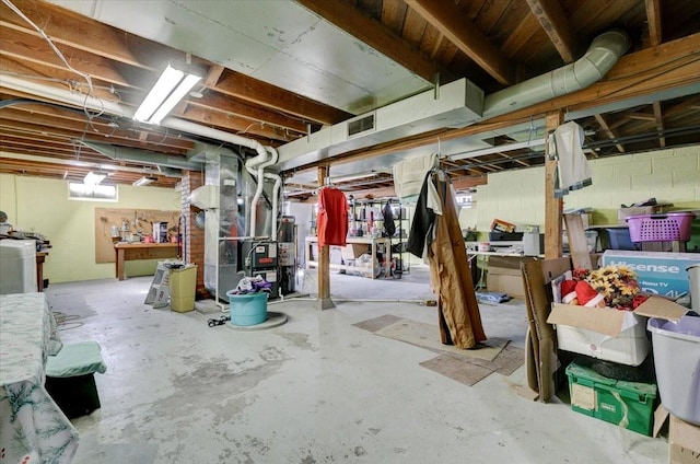 unfinished basement featuring water heater, washer / clothes dryer, visible vents, and heating unit